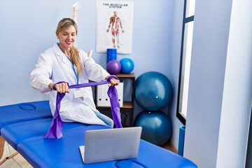 Young blonde woman wearing physiotherpist having online recovery session at physiotherapy clinic