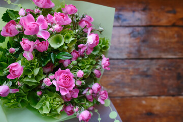 Bouquet of pink-green flowers on a wooden background. Roses top view. Place for text. Holiday postcard. Copy space
