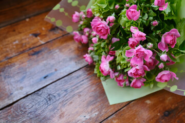 Bouquet of pink-green flowers on a wooden background. Roses top view. Place for text. Holiday postcard. Copy space