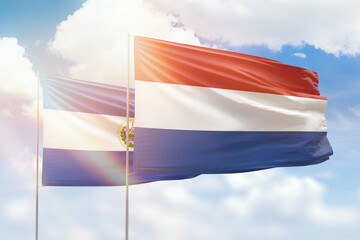 Sunny blue sky and flags of netherlands and el salvador