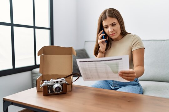 Young hispanic woman talking on the smartphone reciving order at home
