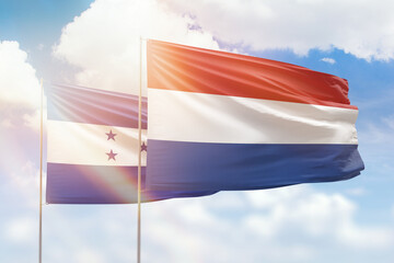 Sunny blue sky and flags of netherlands and honduras