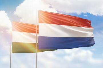 Sunny blue sky and flags of netherlands and hungary