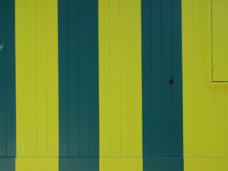 green and yellow striped wooden cabin with a closed shutter