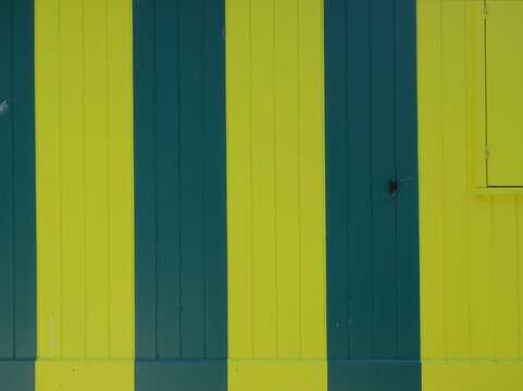 green and yellow striped wooden cabin with a closed shutter