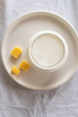 A glass of milk on a table with a white tablecloth. Glass jar with honey and yellow candies.