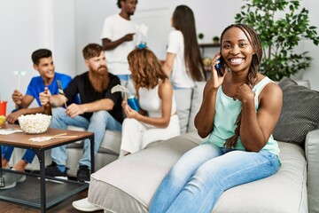 Obraz premium Group of young friends smiling happy sitting on the sofa. Woman using smartphone at home.