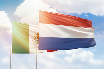 Sunny blue sky and flags of netherlands and mexico