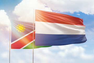 Sunny blue sky and flags of netherlands and namibia