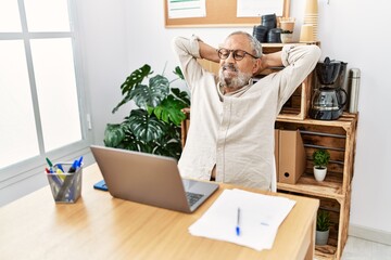 Senior grey-haired man relaxed with hands on head working at office