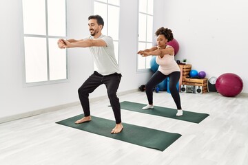 Fototapeta premium Young african american woman and hispanic man exercising at pilates room, stretching body and doing yoga pose, training strength and balance
