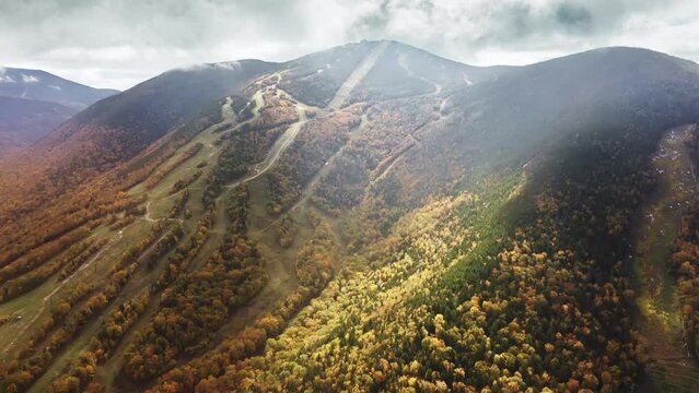 Franconia Notch park, New Hampshire, New England, USA. Aerial view cinematic foliage landscape of mountains covered by fall forest foliage. Cannon mountain ski resort on beautiful sunny autumn day 4K