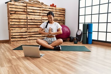 Young latin woman smiling confident having online yoga class at sport center