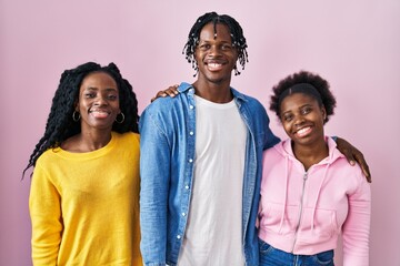 Group of three young black people standing together over pink background winking looking at the...