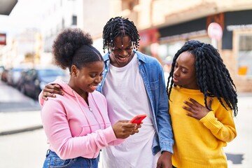 Obraz premium African american friends standing together using smartphone at street