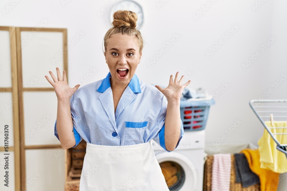 Sticker young caucasian woman wearing cleaner uniform at the laundry room celebrating crazy and amazed for s