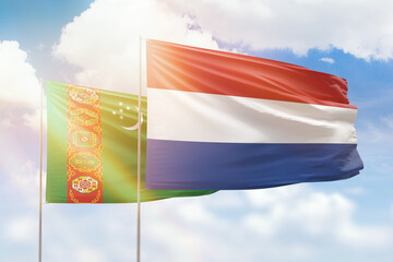 Sunny blue sky and flags of netherlands and turkmenistan