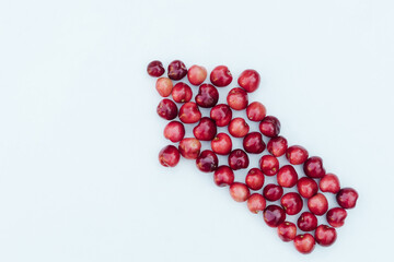 Sweet red cherries on a white background in the shape of an arrow. Ripe fresh red sweet cherry isolated on white background