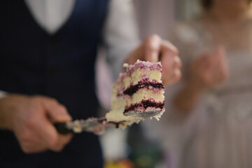 Confectioner cuts a cake. Man holding a piece of cake on a knife