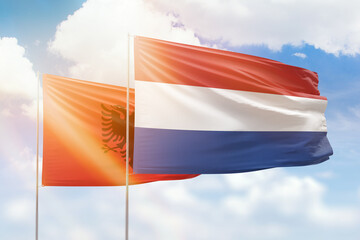 Sunny blue sky and flags of netherlands and albania