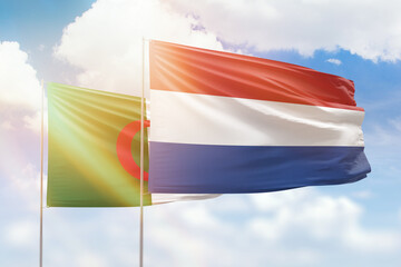 Sunny blue sky and flags of netherlands and algeria