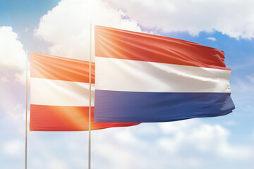 Sunny blue sky and flags of netherlands and austria
