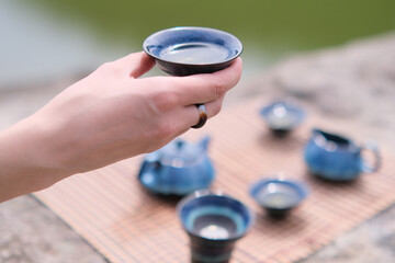 Girl hand holding blue cup with tea. A tea ceremony at rocks.