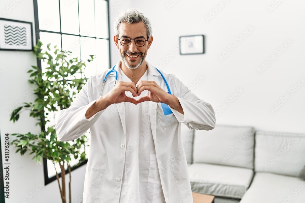 Sticker middle age hispanic man wearing doctor uniform and stethoscope at waiting room smiling in love doing