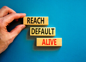 Reach default alive symbol. Concept words Reach default alive on wooden blocks on a beautiful blue table blue background. Businessman hand. Business, finacial and reach default alive concept.
