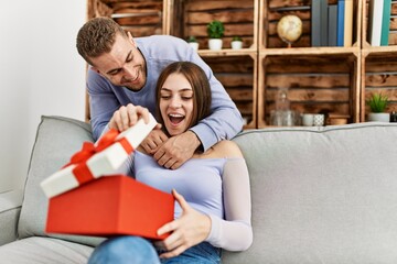 Young man surprising his girlfriend with birthday gift at home.