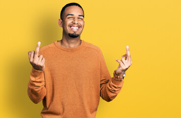 Young african american man wearing casual clothes showing middle finger doing fuck you bad...