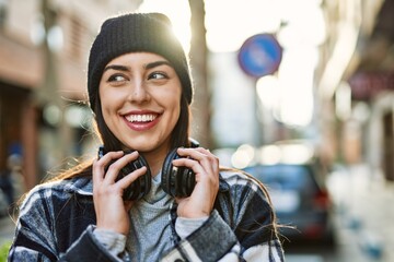 Young hispanic woman smiling happy using headphones at the city.