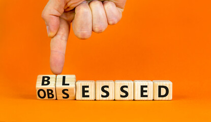 Blessed or obsessed symbol. Businessman turns wooden cubes and changes the concept word Obsessed to Blessed. Beautiful orange table orange background. Business blessed or obsessed concept. Copy space.