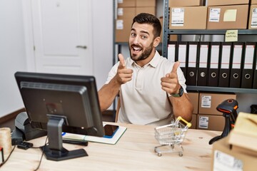 Handsome hispanic man working at small business commerce pointing fingers to camera with happy and funny face. good energy and vibes.