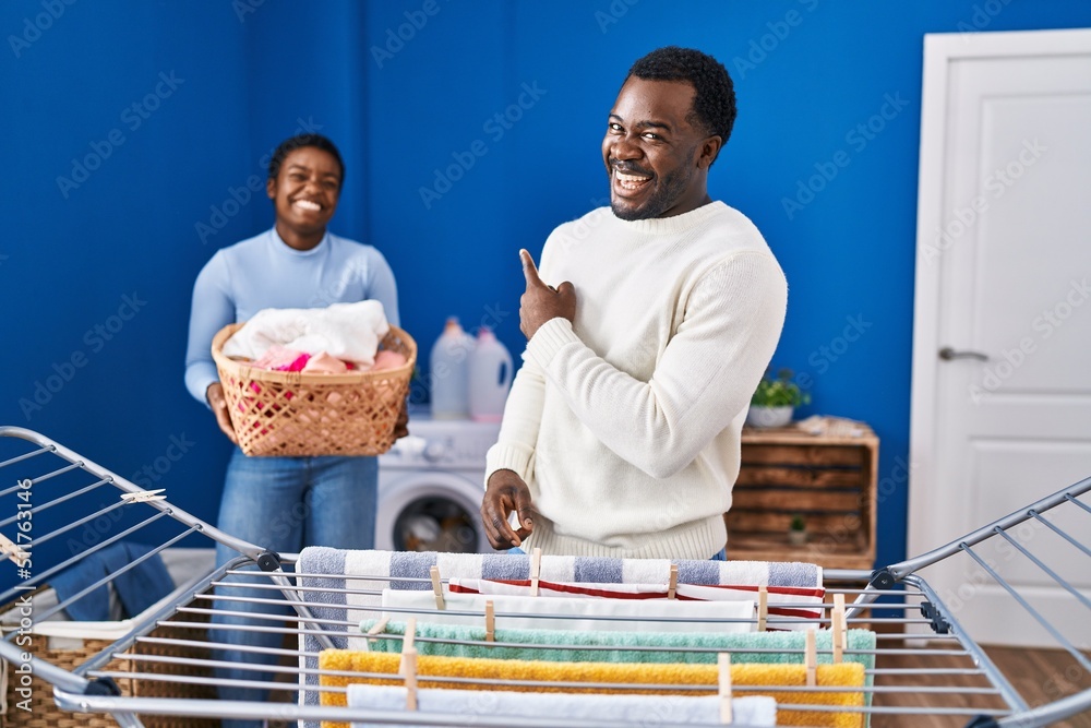 Poster Young african american couple hanging clothes at clothesline smiling happy pointing with hand and finger