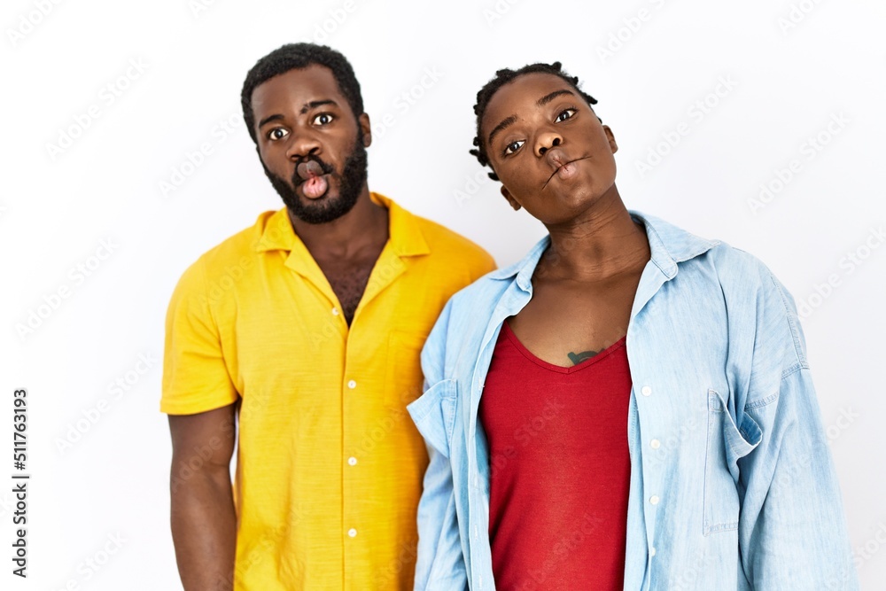 Wall mural Young african american couple wearing casual clothes making fish face with lips, crazy and comical gesture. funny expression.