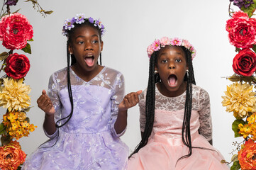 Two sisters with long braids, flower crowns and long dresses shocked and surprised
