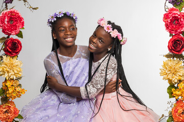 Two sisters with long braids wearing dresses and flower crowns and hugging