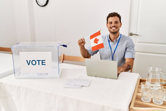 Young hispanic man smiling confident holding canada flag working at electoral college