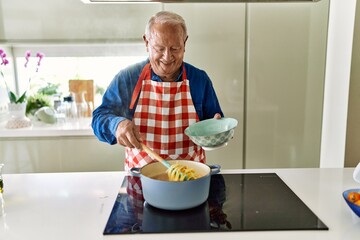 Senior man smiling confident cooking spaghetti at kitchen