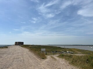 Fototapeta na wymiar Landscape with Martello tower historic stone forts built as 19th century sea defences on East Anglia coastline Aldeburgh beach Suffolk uk with wooden bridge over moat in Summer blue skies 