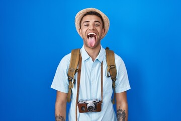 Brazilian young man holding vintage camera sticking tongue out happy with funny expression. emotion...