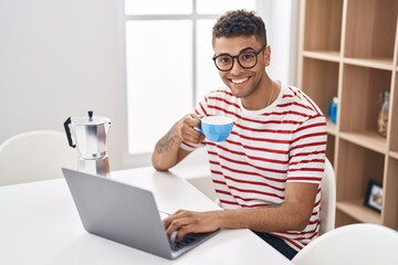 African american man using laptop drinking coffee at home