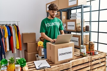 Young arab man wearing volunteer uniform using laptop at charity center