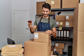 Young hispanic man business worker holding barcode reader machine at storehouse