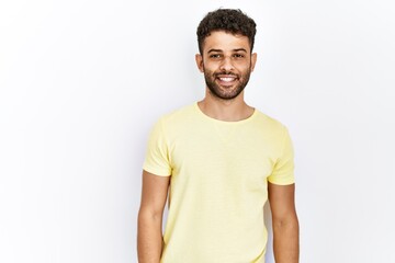 Arab young man standing over isolated background looking away to side with smile on face, natural expression. laughing confident.