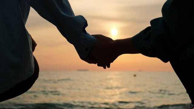 Couple holding hands together. Women holding hands relaxing and walking down the beach at sunrise.