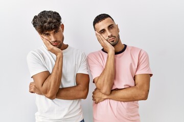 Young gay couple standing over isolated background thinking looking tired and bored with depression problems with crossed arms.