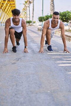 Two hispanic men sporty couple smiling confident on start race position at street