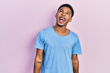 Young african american man wearing casual blue t shirt angry and mad screaming frustrated and furious, shouting with anger. rage and aggressive concept.